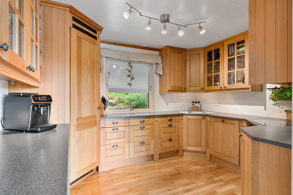 Modern kitchen featuring sleek wooden cabinets, a coffee machine, and ample natural lighting.