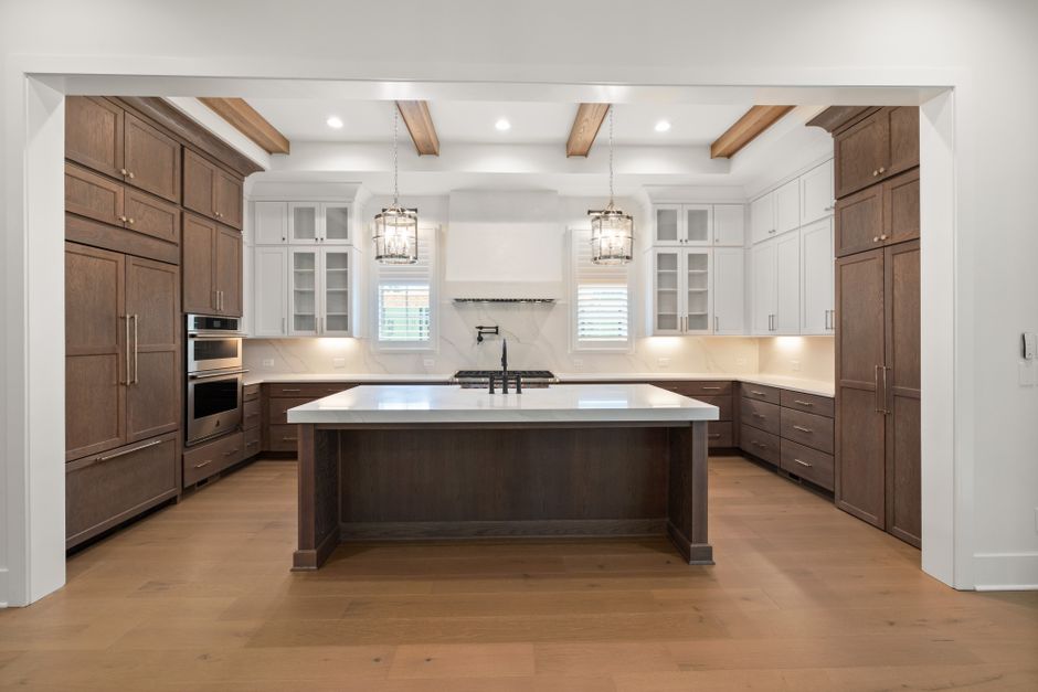Spacious modern kitchen featuring wooden cabinets, island, and pendant lights.